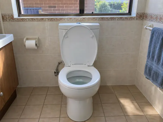 Clean white toilet in a tiled bathroom with a window and towel rail in Rooty Hill