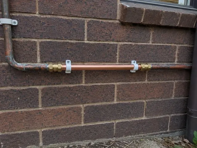 Copper pipe repair fixed along a brick exterior wall beside a window in Mount Druitt